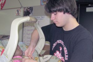 Washougal High School junior Ethan Crone carefully puts the "baby" into an infant carseat during a child development class. Being a self-described "motorhead," the class is a new experience for him but he's enjoyed it for the most part.