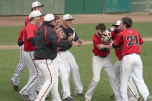 Camas baseball players and coaches celebrate with Justin Webb (center) after he beat out the base hit that won the district title Thursday, at Propstra Park in Vancouver.