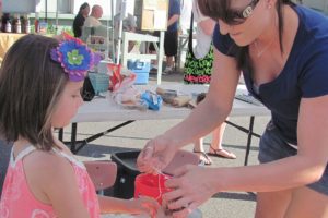 Cape Horn-Skye fifth-grade teacher Chelsea Meats helps Sami Tyler tie a string around her bird feeder, a fundraiser for a school trip to Costa Rica next July.