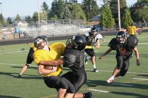 Joe Harris (right) brings down the ball-handler during practice Friday, at Fishback Stadium. Harris was a Washougal High School cheerleader last fall, but now he's in football pads.