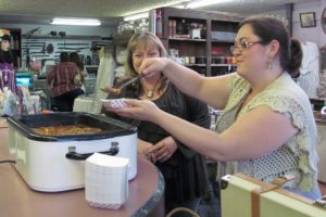 Belle Mathieu (foreground) and Debra Sampson serve "Hot Mana Chili" at A Twist on Time. Sampson, co-owner of the store, said she doesn't use a recipe when cooking it.