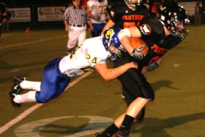 A Crook County defender holds on for dear life, as Washougal High School senior running back Ryan Erdwins explodes for more yards Friday, at Fishback Stadium.