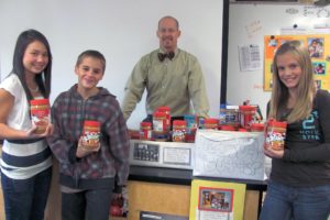 Skyridge Middle School students (left to right) Lindsey Kosaki, Adam Ryan and Kate Fritz are helping with the peanut butter collection efforts organized by science teacher John Condon (background).