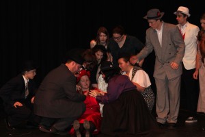 Lady Macbeth (Keira Stogin) faints upon hearing of the king's death while the rest of the cast looks on.