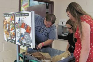 Skyridge Middle School technology teacher Ann Hofmann, and Green Team members (left to right) Sidney Greenamyer and Kaelene Barlow regularly sort through recycling and garbage bins during lunchtime, and remove items that are put in the wrong area.