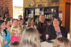 Linda Haines (seated) enjoys a laugh with several fifth-grade girls from Hathaway Elementary School during her "bad manners" skit at K'Syrah restaurant in Camas.