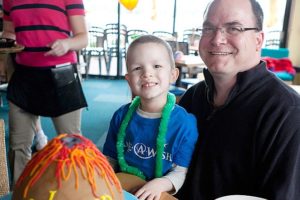 Washougal resident Coleman Merle, 5, sits with his dad, Tim, during a Make-A-Wish Oregon party held at Beaches Restaurant in Vancouver on Friday. It featured beach-themed gifts and a volcano cake donated by Two Little E's Cakes and Goodies of Portland.