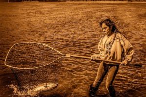 A young member of The Confederated Tribes of Warm Springs helps to land a salmon caught by her younger brother. Photographer Brian Christopher has spent two years capturing images of Native Americans at work and play, which will be on display at the Second Story Gallery in Camas.