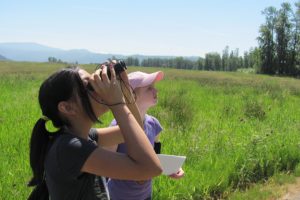 Emmy Campen (front) and Shelby Jolly search for birds during a nature walk at Steigerwald Lake National Wildlife Refuge, located just east of  Washougal.