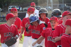 Zach Blair gets a warm greeting from his teammates after hitting a 2-run home run Wednesday, at Forest Home Park. The Camas Little League 9- to 10-year-old all-stars beat Evergreen 10-0 Sunday to become the Washington District 4 baseball champions.