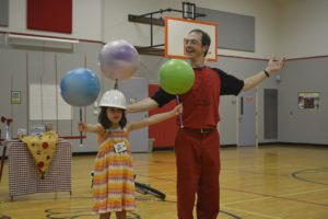 Rhys Thomas shares physics through juggling with children attending a performance at Hathaway Elementary School. Here, Maya Hopkins assists him.