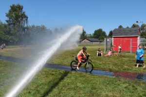 Children gather at Hamllik Park on Addy Street in Washougal to cool off beneath the spray of the Camas and Washougal Fire Department fire hose in 2015. (Post-Record file photo)