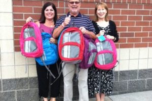 From left, principals Laura Bolt, Rex Larson and Mary Lou Woody display backpacks their schools received, filled with supplies, for children in need.