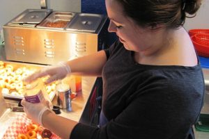 Sarah Arnold, co-owner of Echo Donut Lounge, in downtown Washougal, adds toppings to mini doughnuts. She and Bret Van Horn use a Lil' Orbits SS1200 mini-donut machine. "It is capable of making up to 1,200 donuts per hour, although we don't ever run it that hard," Van Horn said.