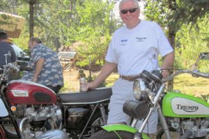 Jim Brownlee stands next to two Triumph motorcycles he restored. The green bike took him three years to complete, as he had to find all the parts to build it. He has restored 17 motorcycles over the years.