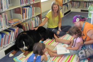 Viviane Deva, 6, and sister, Ave, 8, take turns reading to Cooper. a certified therapy dog, at the Camas Public Library.