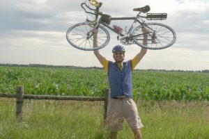 Blair raises his bike in victory after a long , hot day on a bumpy road in central Nebraska.