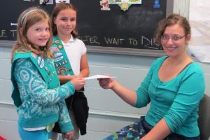 Kendra Short and Syerrah Wilson-Brown (left to right) present a money order to West Columbia Gorge Humane Society volunteer Caitlin Hanky.