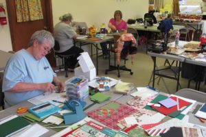 Julia Schlaht (lower left), of Vancouver, made Christmas cards Sunday, in Washougal, at Sew Desperate -- a new venture started by Anna Davis. The rental space provides tables for crafters to complete their projects.