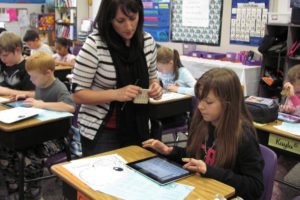 Hathaway Elementary School fifth-grade teacher Erin Hayes assists Consuelo Martinez with a research question. The students in Hayes' class are part of a district-wide iPad pilot group. "The use of technology increases my ability to meet the individual needs of each student," she said.