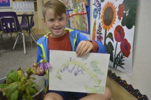 Hathaway Elementary School second-grader Jude Maddox proudly displays his illustration of a foxglove. The students studied botany and then created sketches of different plants.