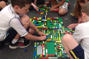 Campers work together to make a giant Lego maze during a summer camp. Teaching children collaboration is one of the skills emphasized by staff at BrickZoneKids.