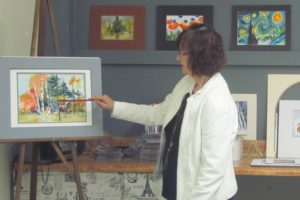 Nancy Ryan demonstrates a painting technique during a recent class. Behind her is student artwork.                                