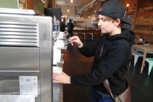 Heidi Armstrong, 22, of Washougal, prepares a cup of salted caramel and cake batter Dannon YoCream frozen yogurt, with assorted toppings, at Smiley's Yogurt and Deli, in downtown Washougal. The new eatery, owned by Paul Le, also offers sandwiches, soups and salads. 