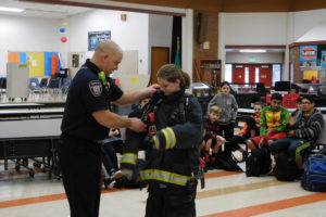 Greg Payne, a firefighter with the Camas-Washougal Fire Department, helps seventh-grader Hailey Bachteler put on the required equipment used for entering a burning structure. It can weigh up to 80 pounds. 