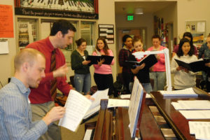 CHS choir teacher Ethan Chessin, right, and composer Luke Wyland work with the students on "Satellite," an original song they will perform at three culminating concerts with Wyland and his band, AU.