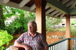 The porch in front of Brian Skinner's home was created using wood from an old log cabin he had salvaged years earlier. Front porches are his "greatest love." 