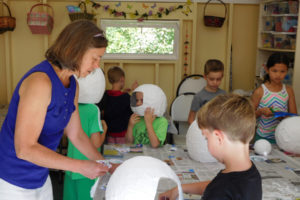 Kathy Marty, director at Camp Windy Hill, assists 6-year-old Dean Lanier with his astronaut helmet during space camp. Marty offers several themed summer camps at her rural Washougal 5 acre property.