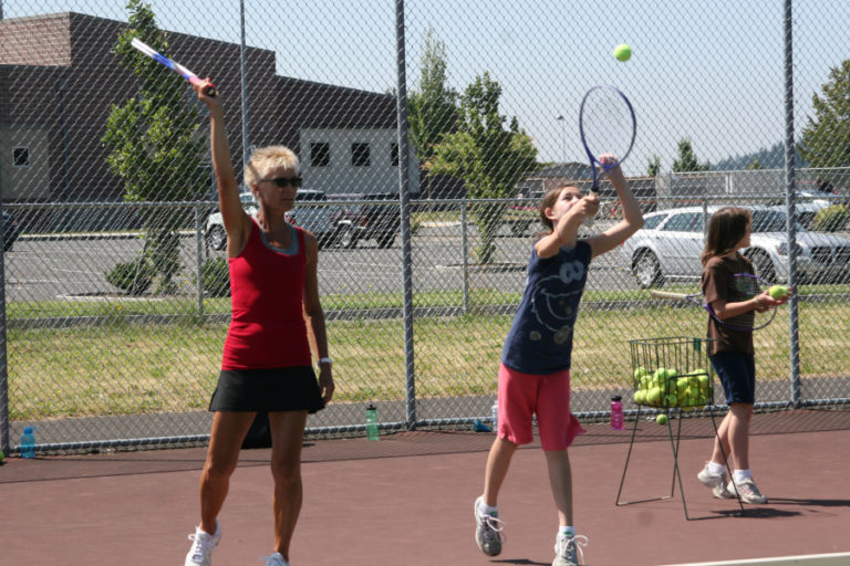Annie Sumpter (left) a CHS tennis coach, instructs an attendee at a youth tennis camp. It is one of the many summer activities offered in the Camas and Washougal areas.