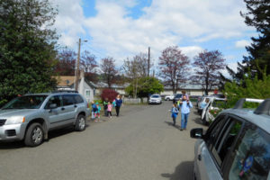 Gause Elementary School students and their parents maneuver around vehicles on the 3400 block of "K" Street, in Washougal, after school April 28. They include RaeShel Peck (left, with her children), who helped bring attention to the issue of K Street needing sidewalks to provide safer passage for children. A public hearing about that proposal, and other potential Community Development Block Grant funded projects, will be held Tuesday, May 9, in front of the Board of Clark County Councilors.