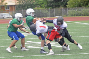 Camas High School football players Trevor Bentley and Shane Jamison double up on a tackle during a scrimmage game June 15, at McKenzie Stadium in Vancouver.