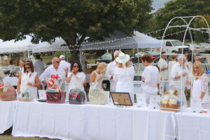 Attendees of the Dinner in White on the Columbia view silent auction items, Sept. 9 at Marina Park, in Washougal. The event served as a fundraiser for a new library in Washougal. (Contributed photo courtesy of Terri London)