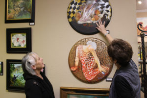 Italian artist Maria Grazia Repetto (left) discusses her artwork, painted on round canvasses she found in the Southwestern United States, with Camas Gallery co-owner Marquita Call (right) on Friday, Dec. 29. The gallery is featuring Repetto's art throughout the month of January, and will host an art reception during First Friday, from 5 to 8 p.m., Jan. 5.