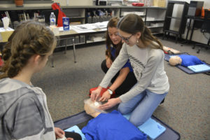 Washougal High students Elizabeth Lewis (left) and Alexandria Kneipp (right) work with Michelle Kruse (right, background) on their CPR training. (Contributed photos courtesy of Rene Carroll)