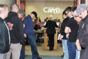 Local firefighters hang their heads in respect as the widow of a Camas man who recently died after a fire at their Camas home, speaks to the Camas City Council on Monday, March 19, about providing funds to have at least three firefighters on each engine for all types of calls. 