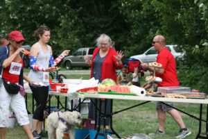 Race organizer Janell Hoglan-Stanton (center) prepares post-race refreshments at the Heroes' Challenge on July 4. 