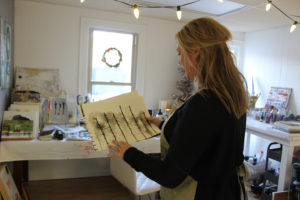 Heidi Jo Curley shows the recent sketches she's done for her father, Jim, inside her new Camas art studio above Arktana shoe store on Northeast Fourth Avenue. 