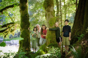 Treesong Nature Awareness and Retreat Center founder Michelle Baumann (second from left) and four children immerse themselves in a "community circle" of trees by the Washougal River in 2016. Treesong will host a variety of "Nature Adventures" day camps that include storytelling, art, movement, singing and nature awareness activities this summer. (Post-Record file photos)