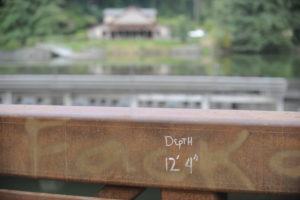 (Photo by Wayne Havrelly/Post-Record)
A depth of 12 feet, 4 inches is recorded on a pedestrian bridge crossing Lacamas Lake in Camas. The city of Camas’ Lacamas Lake Lodge and the Northeast Everett Street vehicle bridge are pictured in the background. Police say a 14-year-old boy who had been jumping off this bridge and swimming in Lacamas Lake Tuesday evening died from an apparent drowning. 