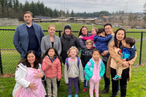 (Photo by Kelly Moyer/Post-Record)
Woodburn Elementary School families gather with their young children in front of the Camas school in early December. Dozens of Woodburn parents have become concerned over a proposal to place a 120-foot cell tower near the elementary school. Pictured (back row,  left to right): Eric Preisz; Cheryl Preisz; Tammy Distler; Tanya Ligouri holding her daughter, Charlotte; and James Jang holding his son, Patrick. Pictured (front row, left to right): Juli Talbert holding her infant, Banks; Tatum Talbert; Lily Distler; Lincoln Ligouri; Florence Jang; and Abigail Jang holding her son, Quentin.