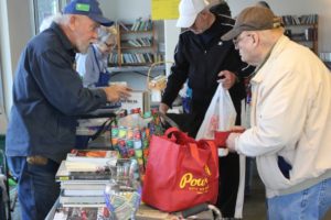 Glenn Thompson of Friends of Washougal Community Library (left) assists a customer during a book sale in downtown Washougal on Friday, Feb.  28. (Photos by Doug Flanagan/Post-Record)