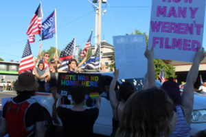 Black Lives Matter counterprotesters hold signs stating: "Hate has no home here" and asking "How many weren't filmed" in downtown Camas on Friday, Aug. 28. In the background, a pickup truck filled with "Back the Blue" supporters waving an assortment of flags passes by on Northeast Third Avenue. (Photos by Kelly Moyer/Post-Record)