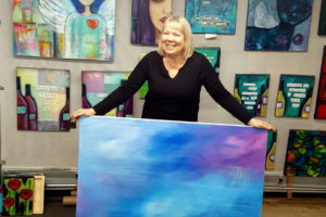 Painter Tamara Dinius holds an oil painting in her Washougal art studio. (Contributed photo courtesy of Tamara Dinius)