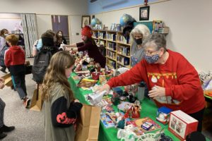 Volunteers Anna Paul left) Linda Davidson (center) and Pam Clark (right) help Hathaway Elementary School students choose presents for their families at the school's annual holiday shop in December 2021. (Photo courtesy of the Washougal School District)