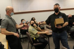 Kindness 911 founder Jason Hattrick (right) gives a box of "kindness citations" to Washougal police officer Kelly Anderson on Feb. 22, 2022. (Doug Flanagan/Post-Record)