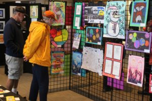 Attendees look at student artwork during the 2022 Washougal Youth Arts Month gallery exhibit at Washougal High School on Wednesday, March 23, 2022. The exhibit served as the culmination of Washougal Youth Arts Month (WYAM), created in 2019 by the Washougal School District, the Washougal Arts and Culture Alliance (WACA), the Washougal Schools Foundation and the city of Washougal. "The Washougal Arts and Culture Alliance has a wonderful partnership with our schools and have funded and helped facilitate a number of student-created public art pieces," WACA board member Rene Carroll said. "But our favorite collaboration is WYAM and the gallery specifically.  The level of talent these young artists exhibit is impressive. It is wonderful to help share this work with the community and give students recognition for their efforts." The gallery featured artwork in a variety of forms, including multimedia, watercolor, clay, video, photography, metal and wood, as well as a loom for visitors to create fabric art for a community weaving project. The student-operated Panthers' Cafe served entrees on Wednesday, March 23, and appetizers on Saturday, March 26, and Washougal High School choir students Lily Barrett and Megan West sang one song each on the final day of the event. (Photos by Doug Flanagan/Post-Record)